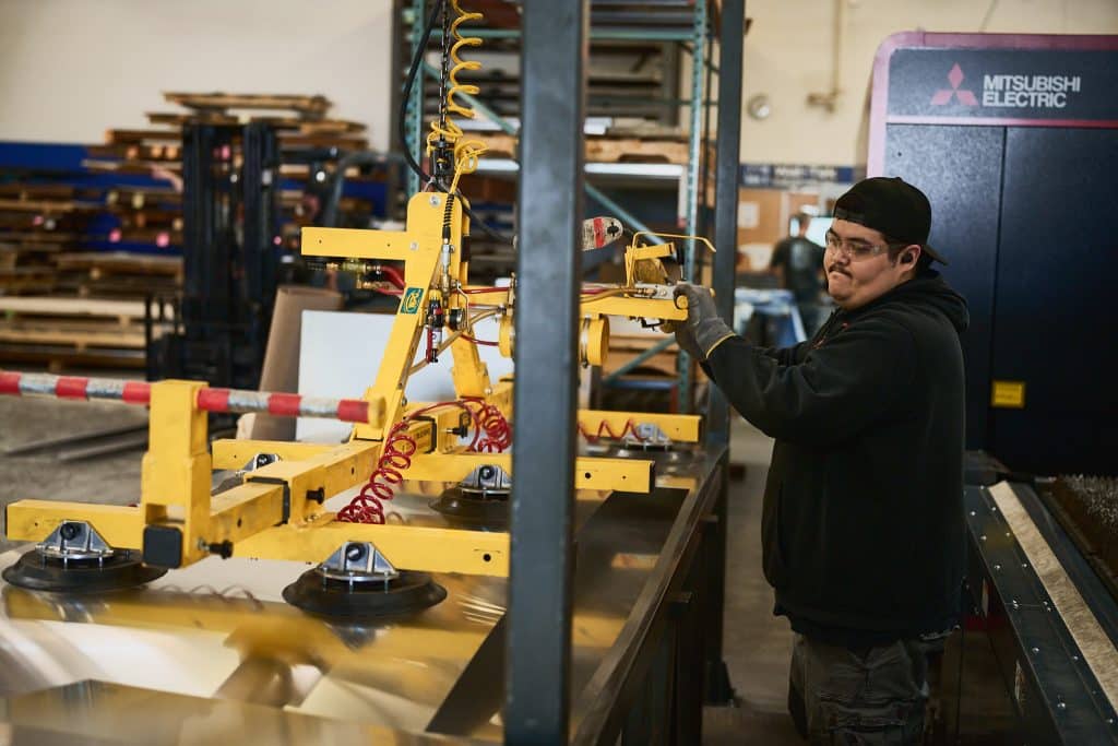 Machinist using a machine to pick up raw sheet metal